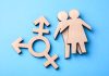 Wooden transgender symbol and couple figures on blue background.