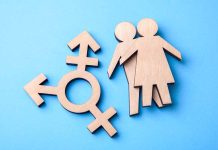 Wooden transgender symbol and couple figures on blue background.