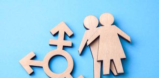 Wooden transgender symbol and couple figures on blue background.