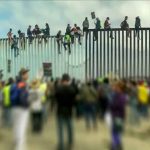 People sitting on high metal fence during protest