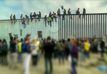 People sitting on high metal fence during protest