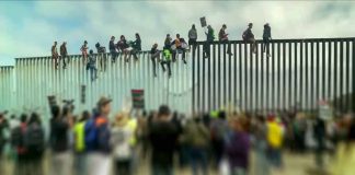 People sitting on high metal fence during protest