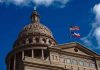 Texas capitol with US and Texas flags, blue sky