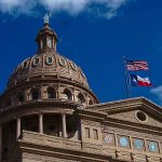 Texas capitol with US and Texas flags, blue sky