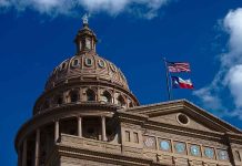 Texas capitol with US and Texas flags, blue sky