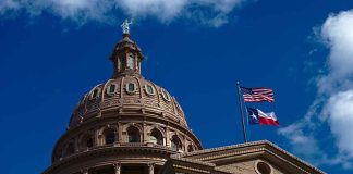 Texas capitol with US and Texas flags, blue sky