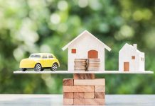 Toy car and houses balanced on stacked coins.