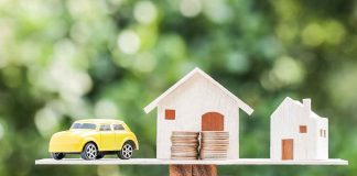 Toy car and houses balanced on stacked coins.