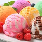 Assorted ice cream scoops with raspberries on a plate.