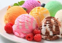 Assorted ice cream scoops with raspberries on a plate.