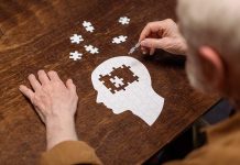 Elderly person completing head-shaped jigsaw puzzle.