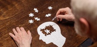 Elderly person completing head-shaped jigsaw puzzle.