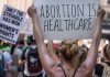 Protestors holding signs about women's rights and healthcare.