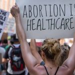 Protestors holding signs about women's rights and healthcare.