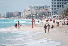 People walking and relaxing on a crowded beach.