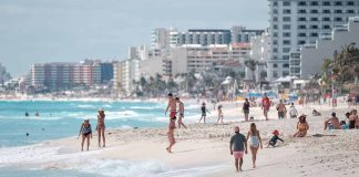 People walking and relaxing on a crowded beach.