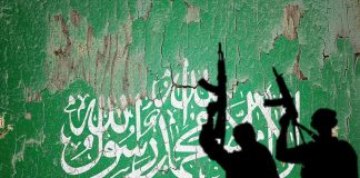 Silhouettes with rifles over Saudi flag background.