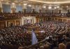 Large assembly in a government legislative chamber.