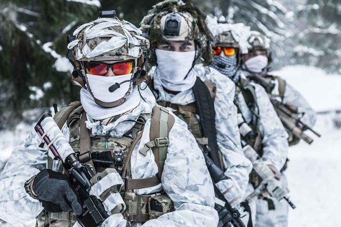 Soldiers in snow camo gear in snowy forest.