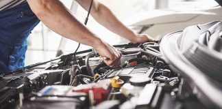 Mechanic working on an engine in a car.