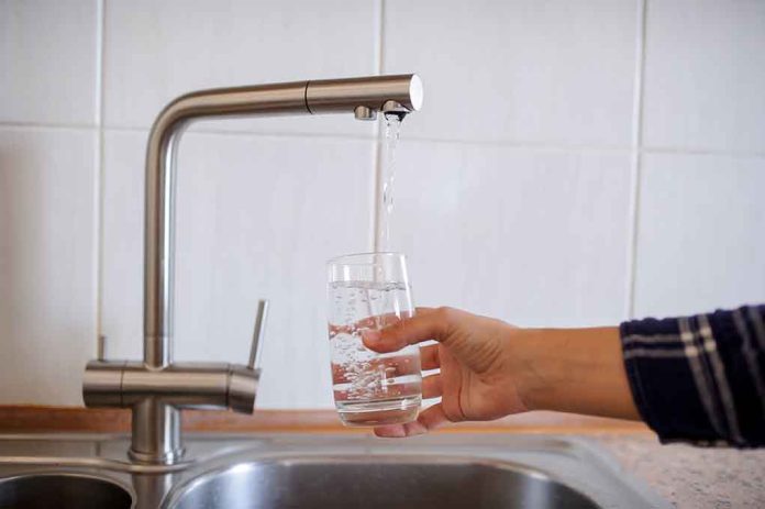 Hand filling glass with water from faucet.