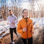 Two people jogging on a snowy path outdoors