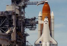 Space shuttle on launch pad with support structure.