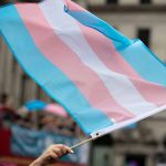 Transgender flag waving in a crowded street.