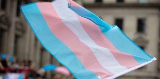 Transgender flag waving in a crowded street.