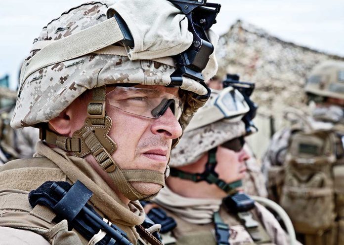 Military personnel in camouflage gear and helmets outdoors