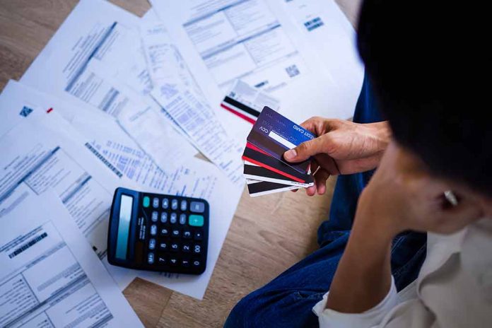 Person holding credit cards amidst bills and calculator