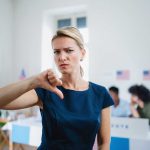 Woman with thumbs down in voting location.