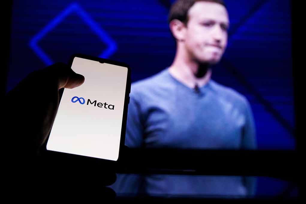 Phone displaying Meta logo person in background