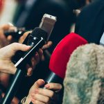 Close-up of various microphones held towards a person.