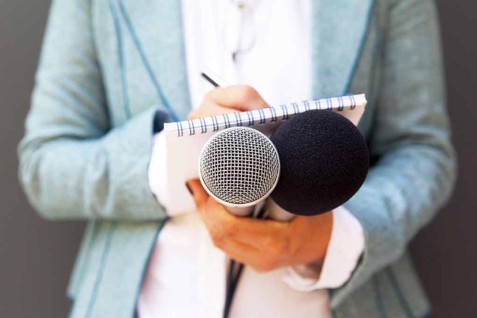 Person holding microphones and a notepad.