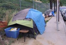 Tents and belongings set up along sidewalk.