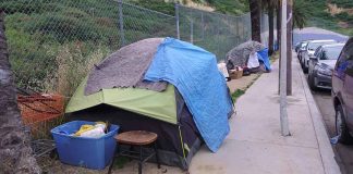 Tents and belongings set up along sidewalk.