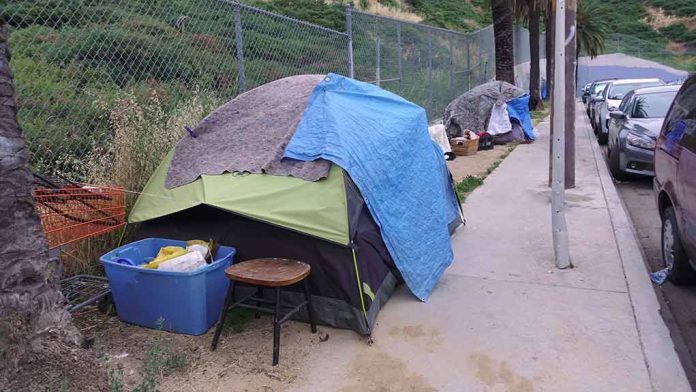 Tents and belongings set up along sidewalk.