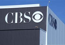 CBS logo on building exterior under blue sky.