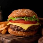 Cheeseburger with fries on a wooden board.