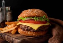 Cheeseburger with fries on a wooden board.