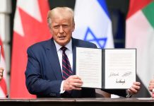 Person in blue suit holding signed document in ceremony