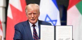 Person in blue suit holding signed document in ceremony