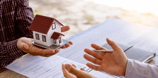 Hands exchanging house model over documents and calculator