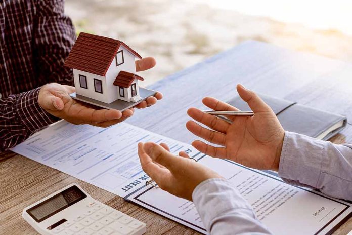 Hands exchanging house model over documents and calculator