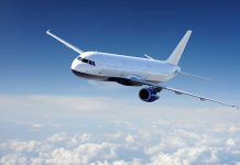 Airplane flying above clouds in blue sky