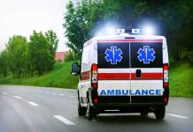 Ambulance driving on a paved road with lights flashing