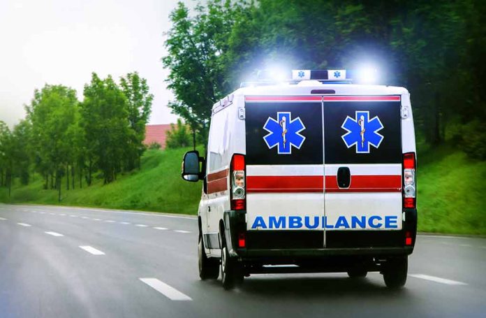 Ambulance driving on a paved road with lights flashing