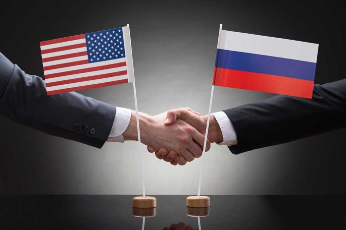 Two people shaking hands with flags displayed